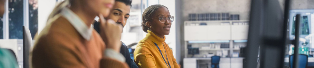 Mehrere Menschen sitzen in einem Büro vor ihren PCs